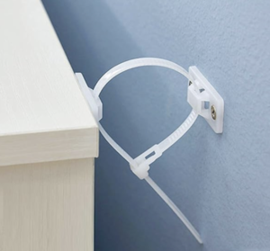 A white cable tie mount screwed into the wall secures a desk to the wall.